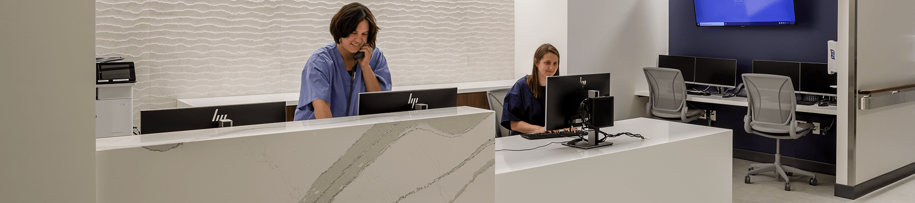 Nurse talks to patient on the phone and receptionist enters data at computer