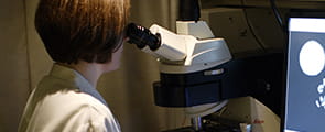 Clinical trials doctor in lab looking through miscrscope