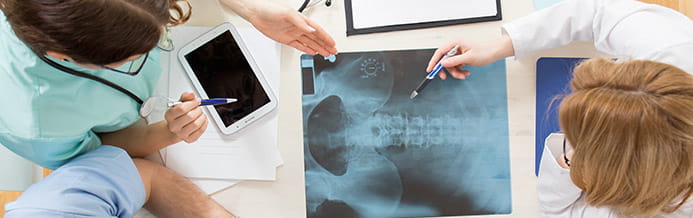 Brain and spine cancer specialists reviewing x-ray to developing a custom treatment plan