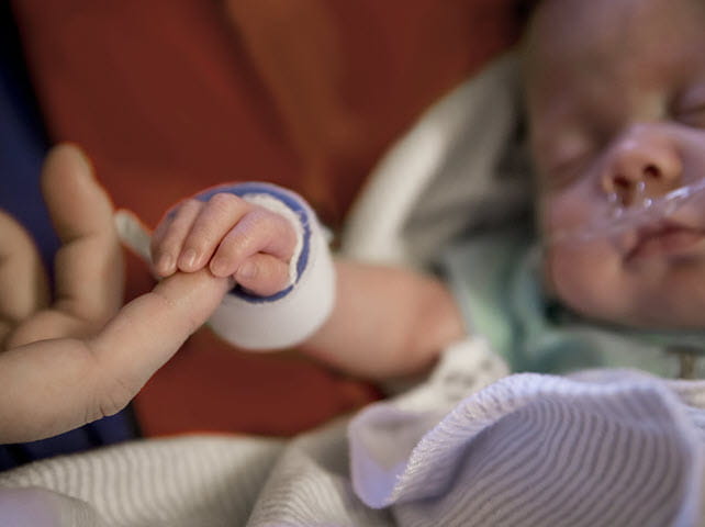 sleeping infant holds fathers hand