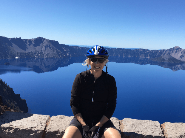 Wendy Berger sitting near Crater Lake, smiling at camera with a bike helmet