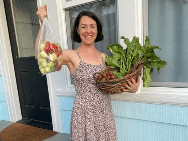 Diana Smith pictured smiling, holding a basket of leafy green vegetables and a plastic bag of apples